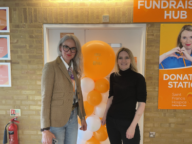 Photo of Julia and Grazina in front of an orange balloon to celebrate 40 years of the hospice during Julia's visit.